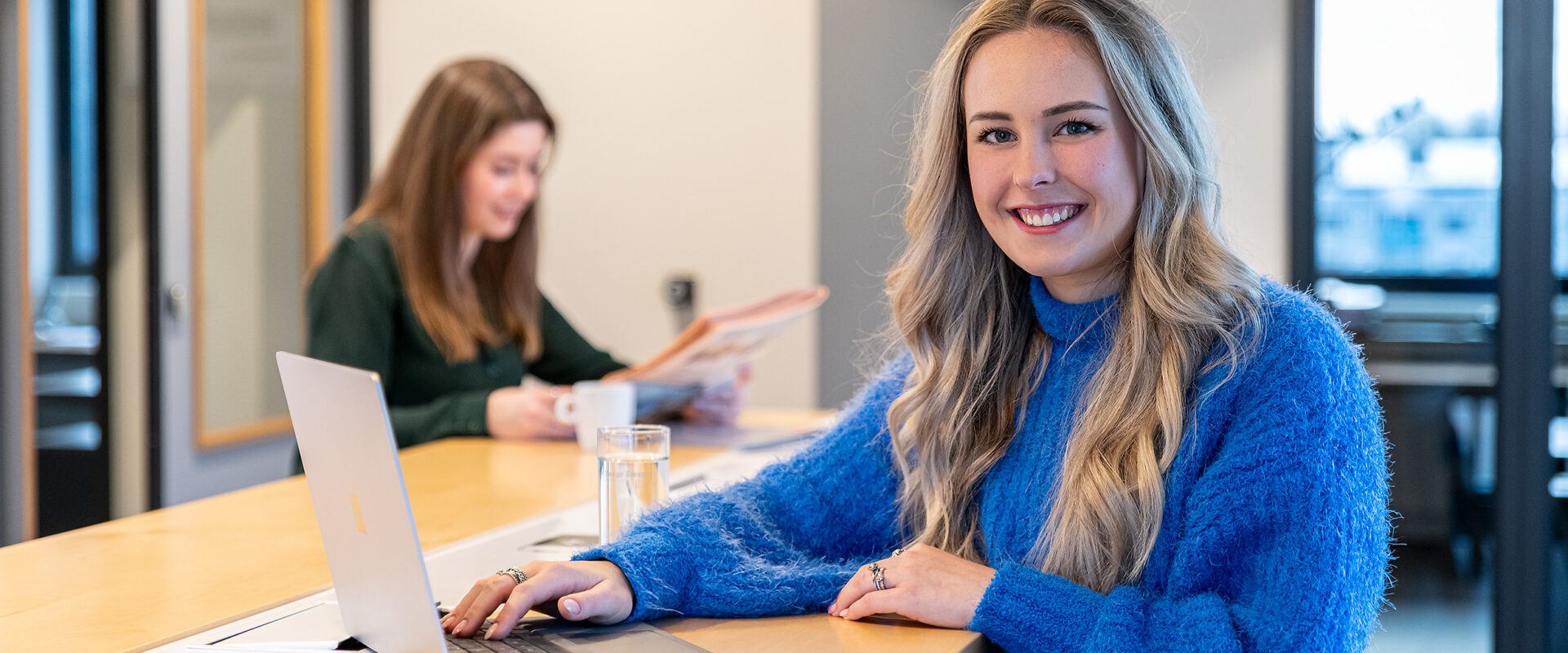 blonde vrouw aan hoge tafel met laptop